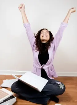 A student celebrating a positive academic opportunity at her study desk